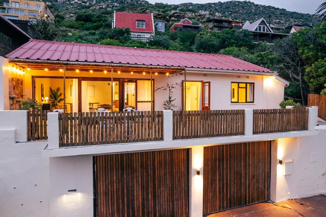 Renovated home on Forrest Way, Glencairn, at dusk: red roof, timber-screened deck and garage, interior lights on