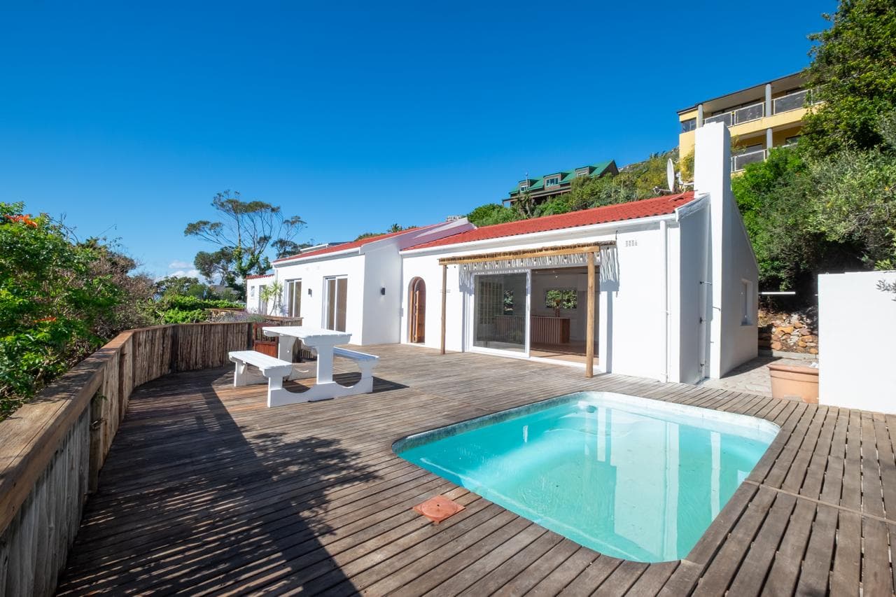 Renovated white home on Wood Way, Glencairn, with red roof, timber deck and pool under a clear sky